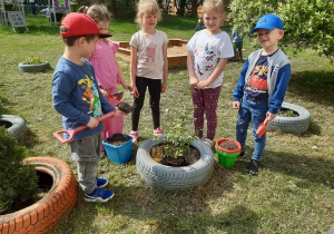 Dzieci sadzą rośliny w ogrodzie przedszkolnym