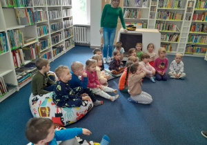 Dzieci siedzą na pufach w dziale dziecięcym w bibliotece