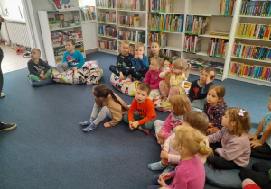 Dzieci siedzą na pufach w dziale dziecięcym w bibliotece