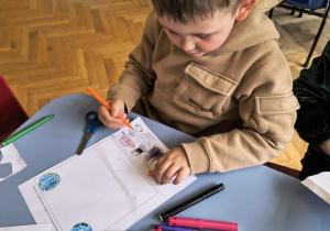 Chłopiec koloruje obrazki.