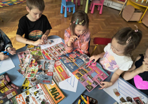 Grupa dzieci wycina produkty z gazet.