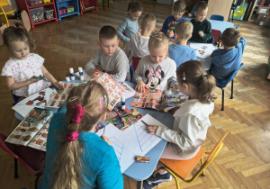Grupa dzieci szuka produktów w gazetkach.