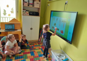 Dzieci rozwiązują zadania na tablicy multimedialnej