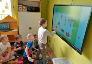 Dzieci rozwiązują zadania na tablicy multimedialnej
