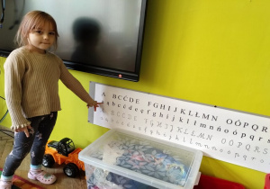 dziewczynka pokazuje mała literkę a pisaną
