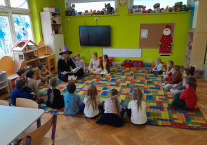 Dzieci słuchają książki czytanej przez zaproszonego gościa