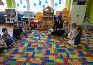 Dzieci słuchają książki czytanej przez zaproszonego gościa