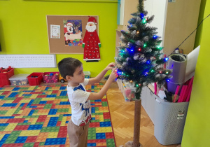 Dziecko zawiesza ozdobę na choince