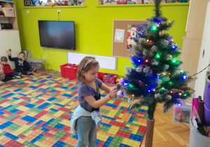 Dziecko zawiesza ozdobę na choince