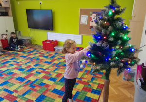 Dziecko zawiesza ozdobę na choince