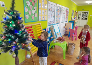 Dziecko zawiesza ozdobę na choince