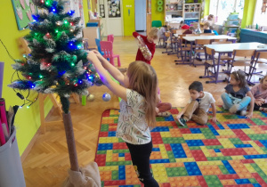 Dziecko zawiesza ozdobę na choince