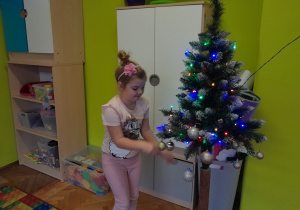 Dziecko zawiesza ozdobę na choince