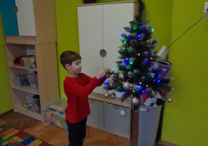 Dziecko zawiesza ozdobę na choince