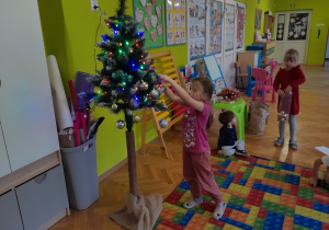 Dziecko zawiesza ozdobę na choince
