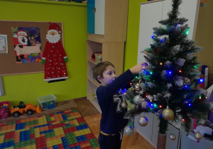 Dziecko zawiesza ozdobę na choince