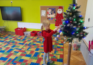 Dziecko zawiesza ozdobę na choince