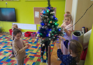 Dzieci zawieszają ozdoby na choince