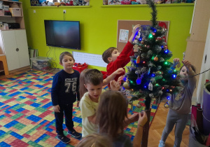 Dzieci zawieszają ozdoby na choince