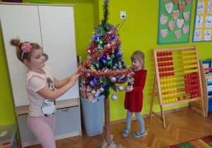 Dziewczynki zawieszają łańcuch na choince