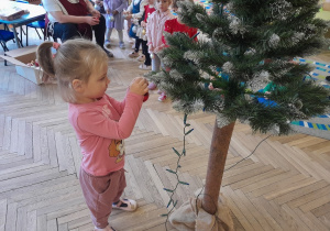 Dziecko zawiesza ozdobę na choince