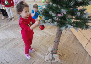 Dziecko zawiesza ozdobę na choince