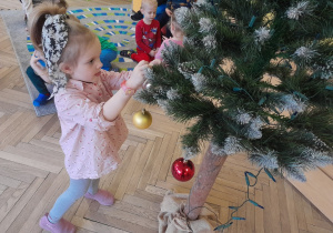 Dziecko zawiesza ozdobę na choince