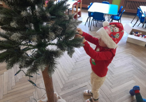 Dziecko zawiesza ozdobę na choince