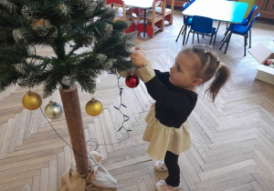 Dziecko zawiesza ozdobę na choince