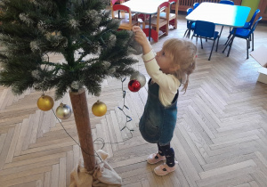 Dziecko zawiesza ozdobę na choince