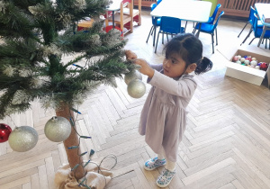 Dziecko zawiesza ozdobę na choince