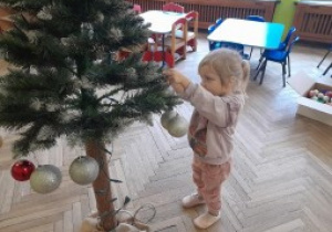 Dziecko zawiesza ozdobę na choince