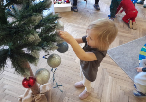 Dziecko zawiesza ozdobę na choince