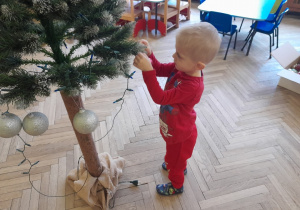 Dziecko zawiesza ozdobę na choince