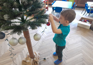 Dziecko zawiesza ozdobę na choince