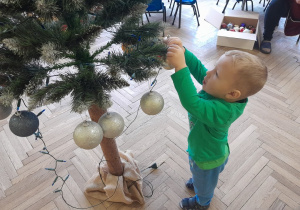 Dziecko zawiesza ozdobę na choince