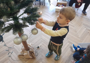 Dziecko zawiesza ozdobę na choince