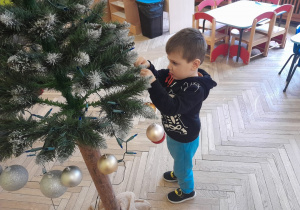 Dziecko zawiesza ozdobę na choince