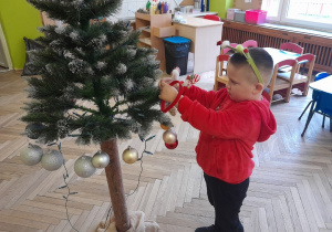 Dziecko zawiesza ozdobę na choince