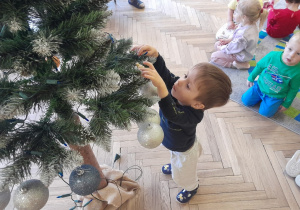 Dziecko zawiesza ozdobę na choince