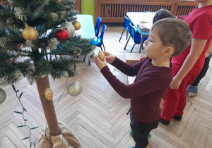 Dziecko zawiesza ozdobę na choince