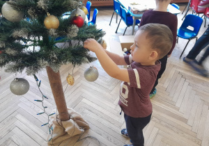 Dziecko zawiesza ozdobę na choince