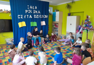 Dzieci słuchają książki czytanej przez zaproszonego gościa