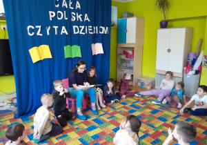 Dzieci słuchają książki czytanej przez zaproszonego gościa