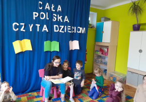 Dzieci słuchają książki czytanej przez zaproszonego gościa