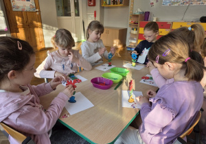 dzieci malują drewniane kwiaty