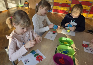 dzieci malują drewniane kwiaty