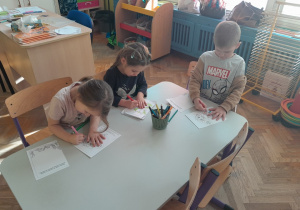 Dzieci wykonują karty pracy do zeszytu o emocjach