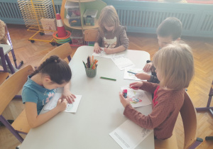 Dzieci wykonują karty pracy do zeszytu o emocjach
