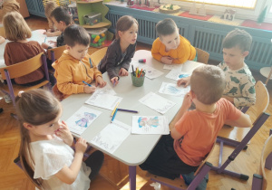 Dzieci wykonują karty pracy do zeszytu o emocjach